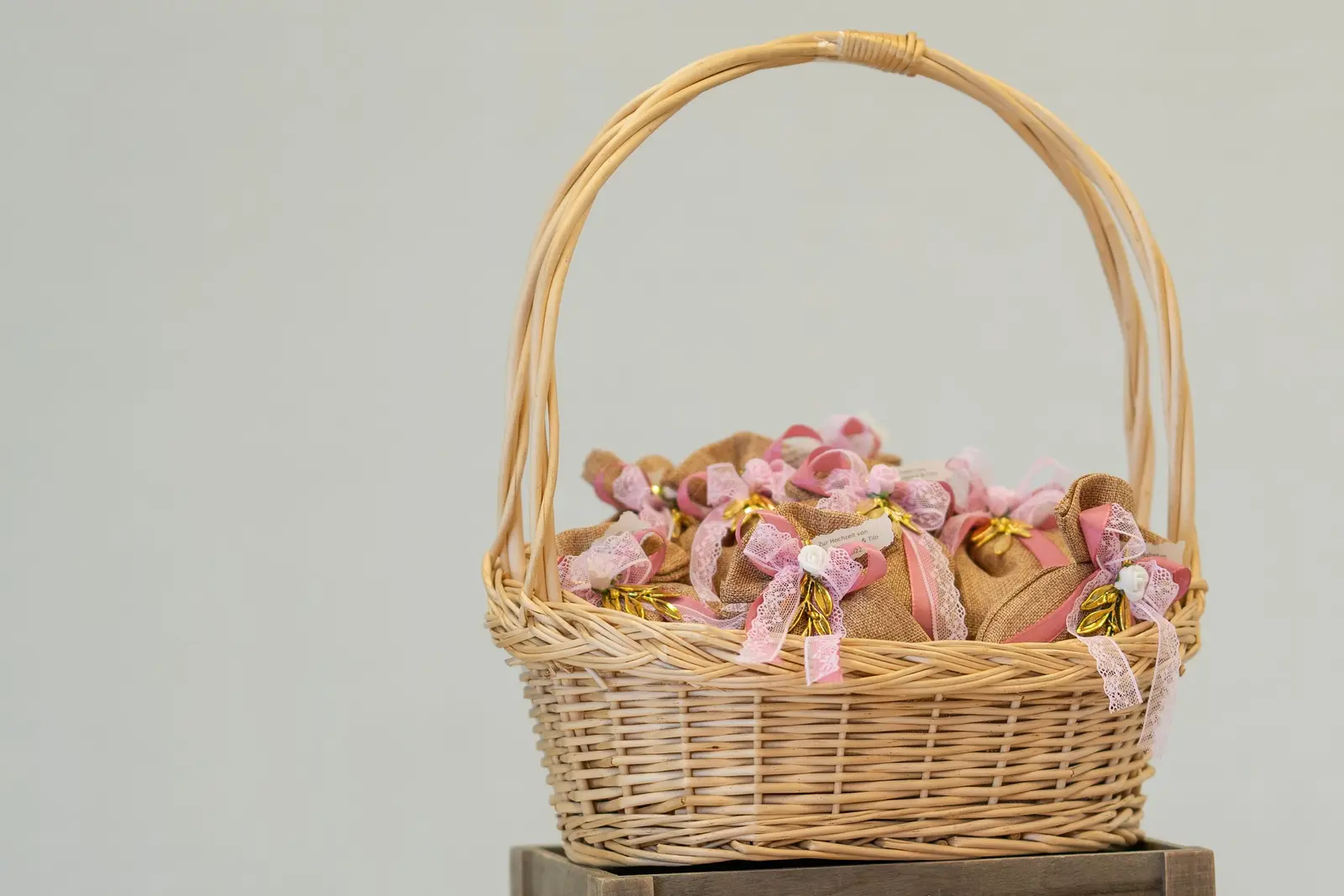 A kraft wicker basket of small gifts tied with pink ribbon
